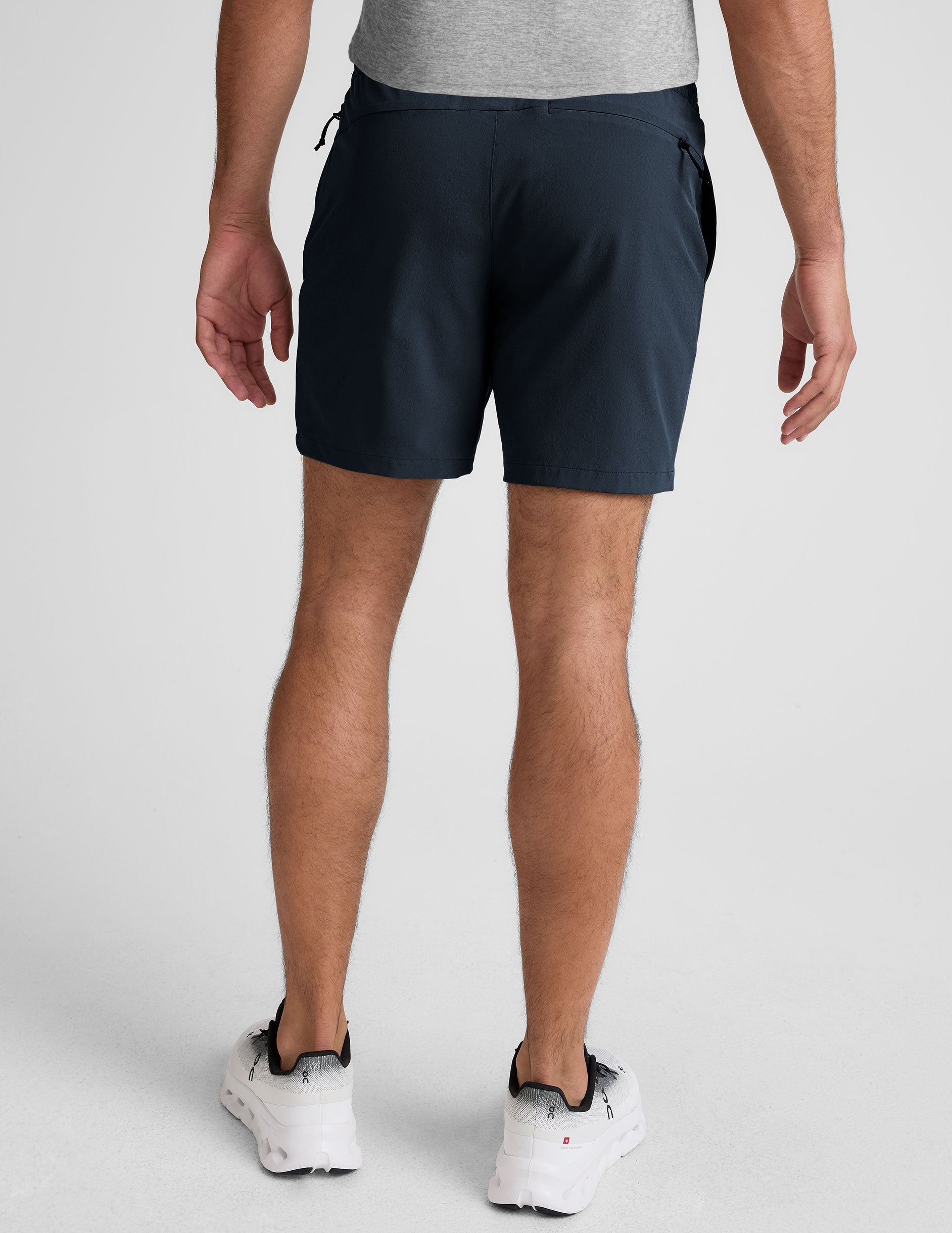 man wearing a navy t-shirt and blue shorts on a white background.