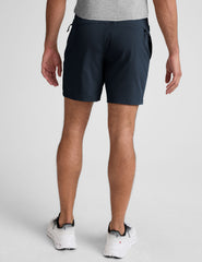 man wearing a navy t-shirt and blue shorts on a white background.