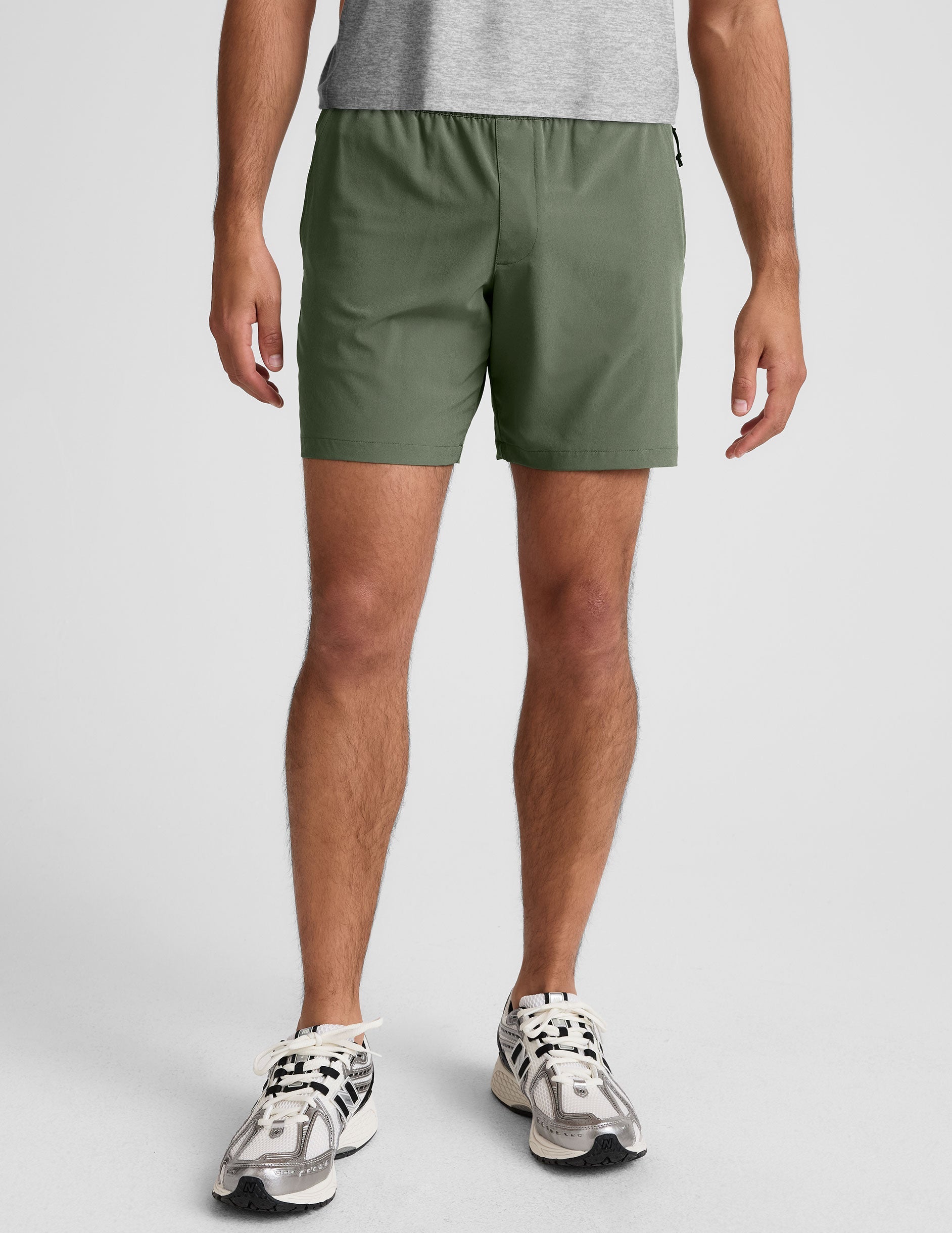 man wearing a gray t-shirt and green shorts on a white background.