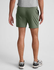 man wearing a gray t-shirt and green shorts on a white background.