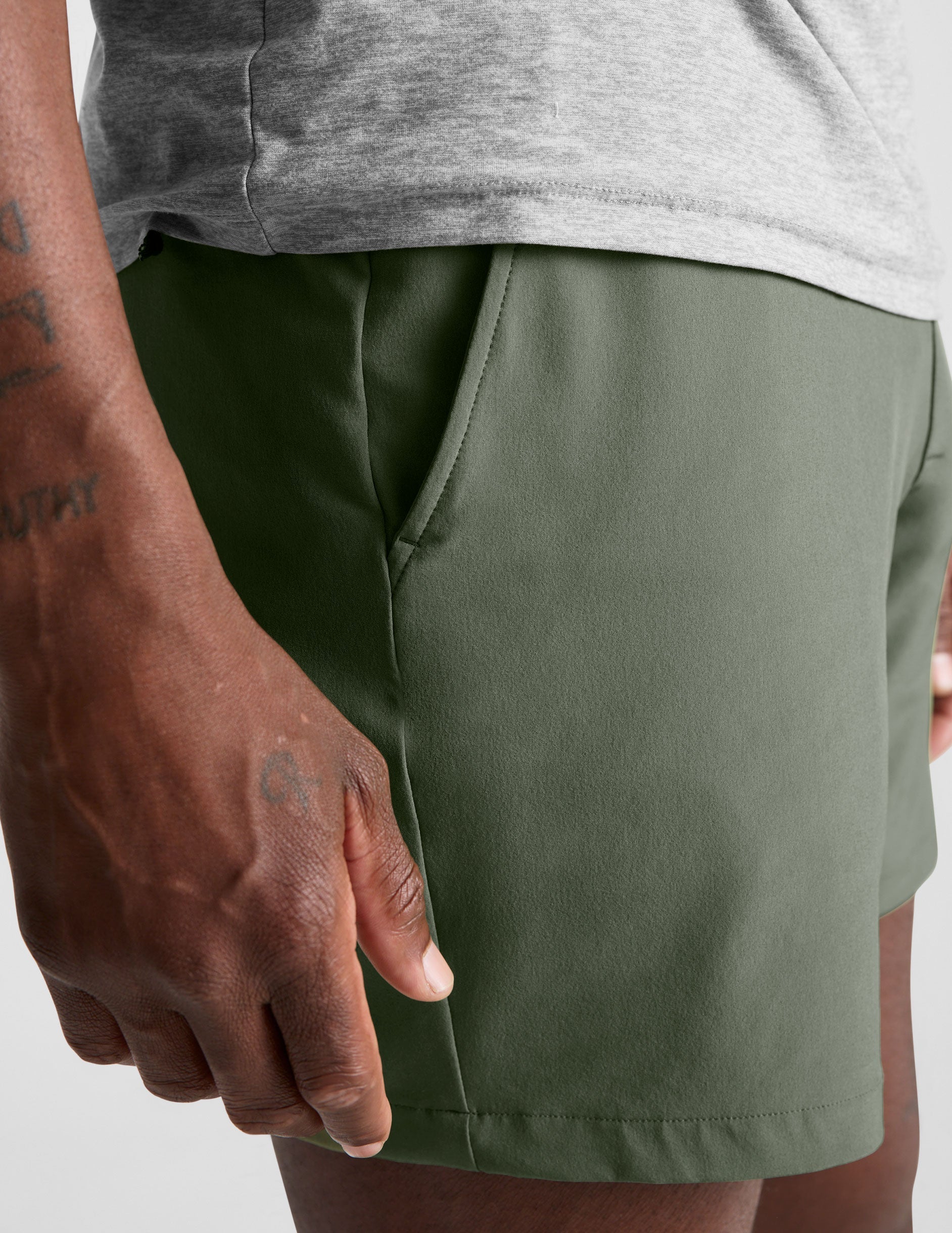man wearing a gray t-shirt and green shorts on a white background.
