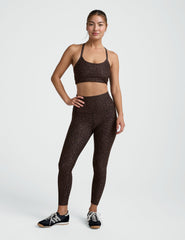 Woman wearing a brown leopard printed  bra and leggings on a plain background.