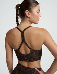 Woman wearing a brown leopard printed  bra and leggings on a plain background.