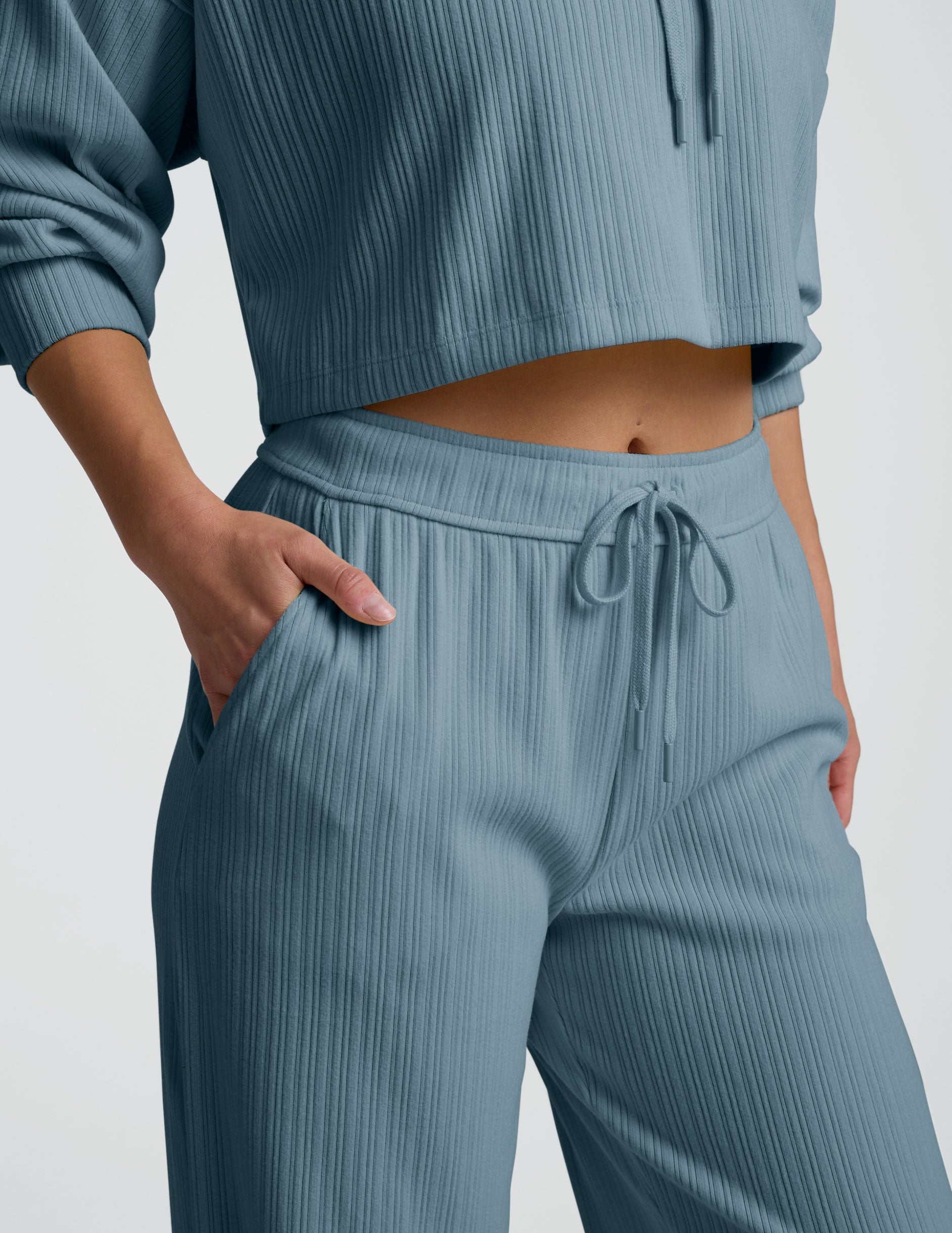 Person wearing a blue ribbed hoodie and pants on a white background.