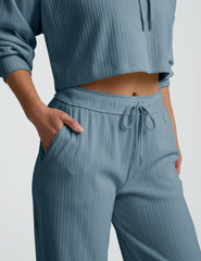 Person wearing a blue ribbed hoodie and pants on a white background.