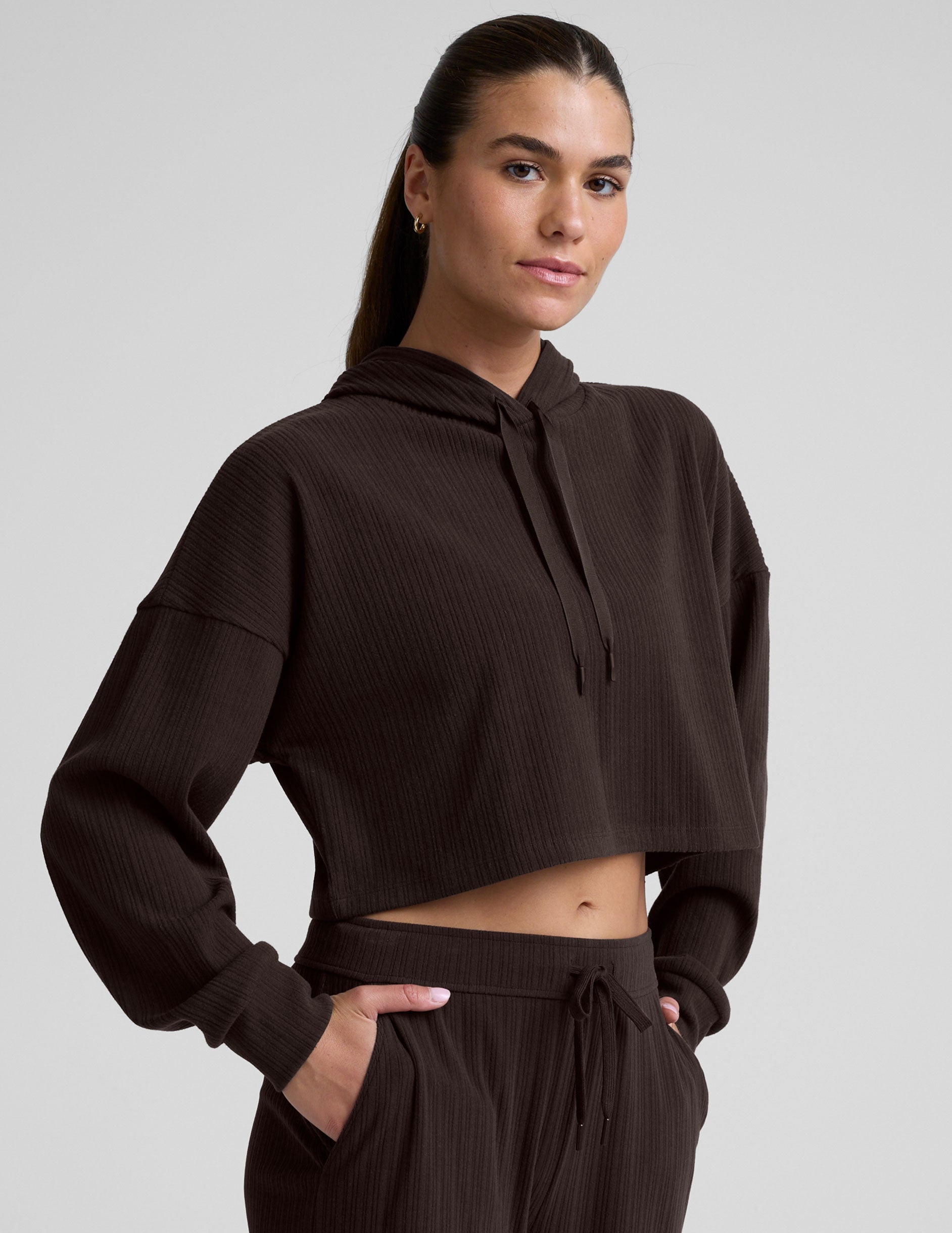 model wearing a brown ribbed cropped hoodie against a plain background.