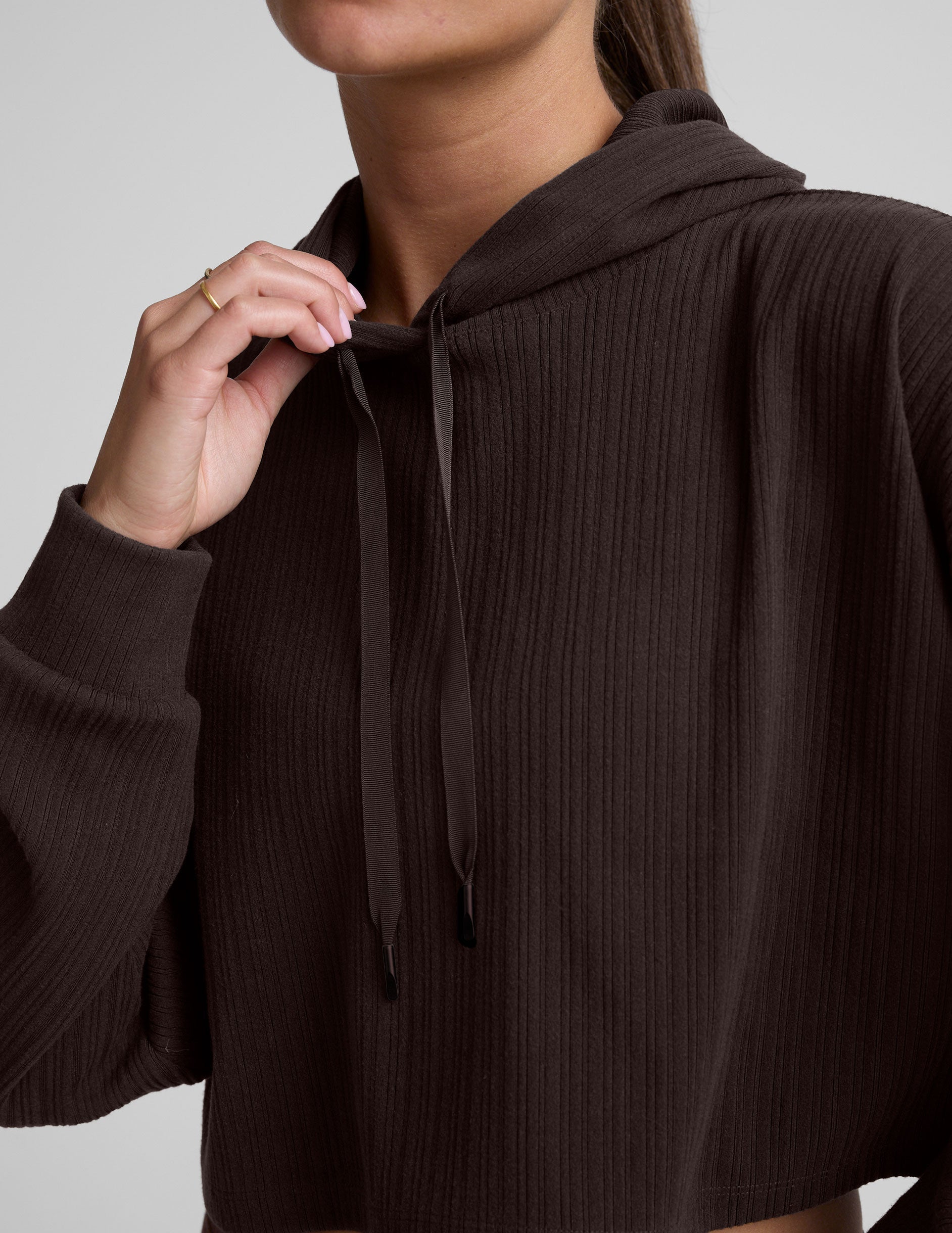 model wearing a brown ribbed cropped hoodie against a plain background.