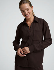 model wearing a brown ribbed button down top and brown ribbed pants against a plain background.