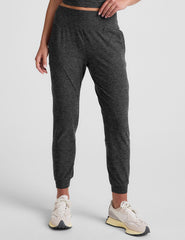woman wearing a dark gray joggers on a plain background.