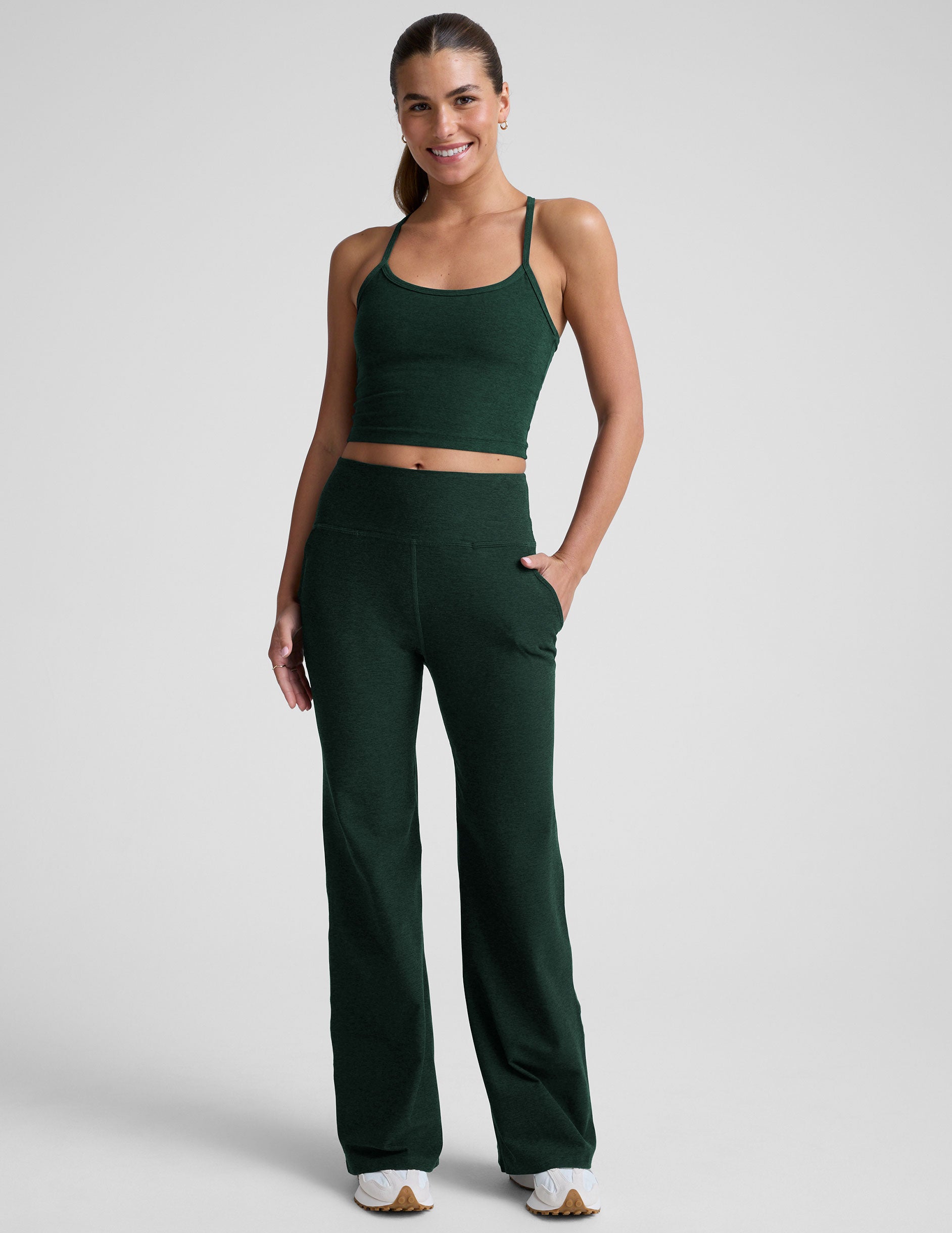 model wearing dark green high-waisted wide leg pants with pockets on a plain background.