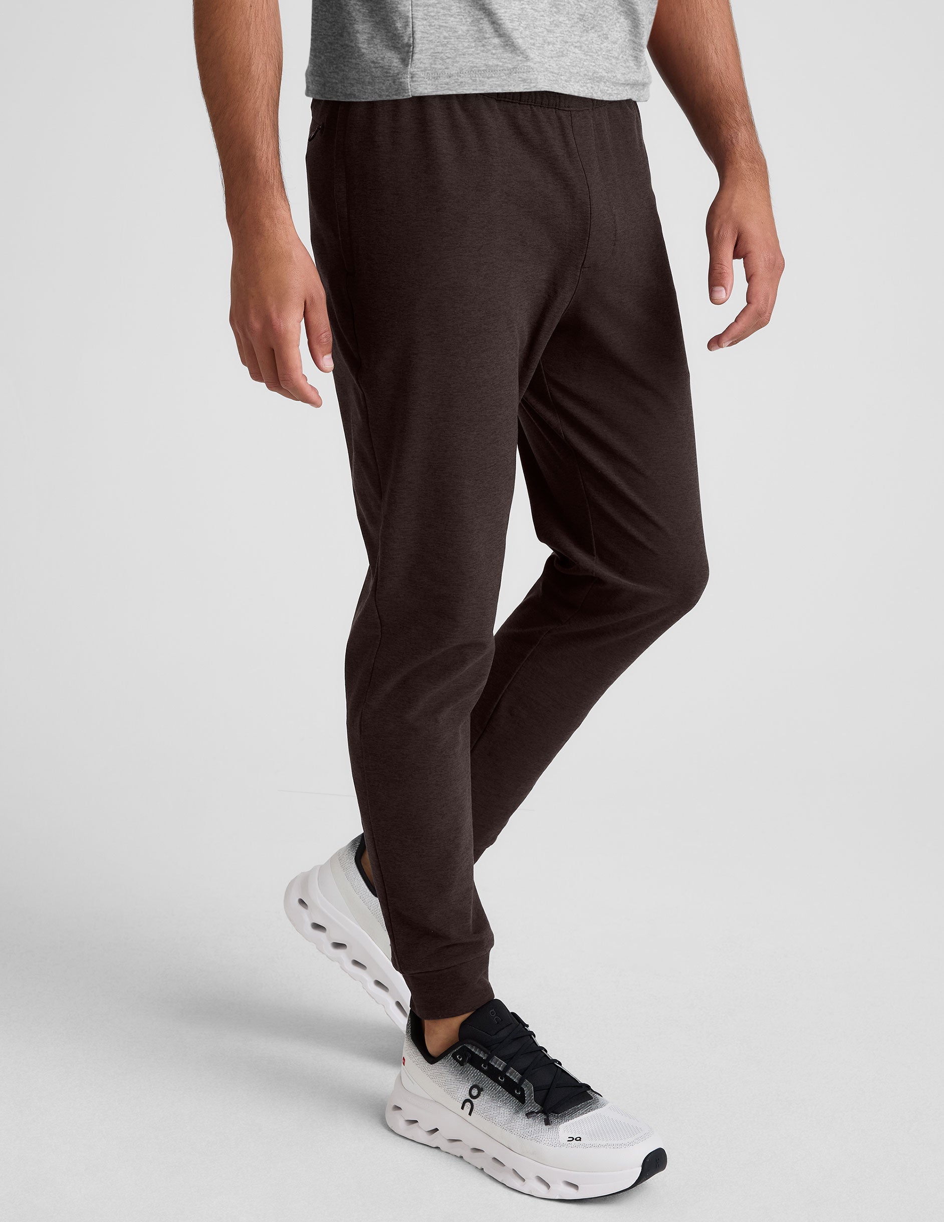 man wearing brown joggers on a plain background.