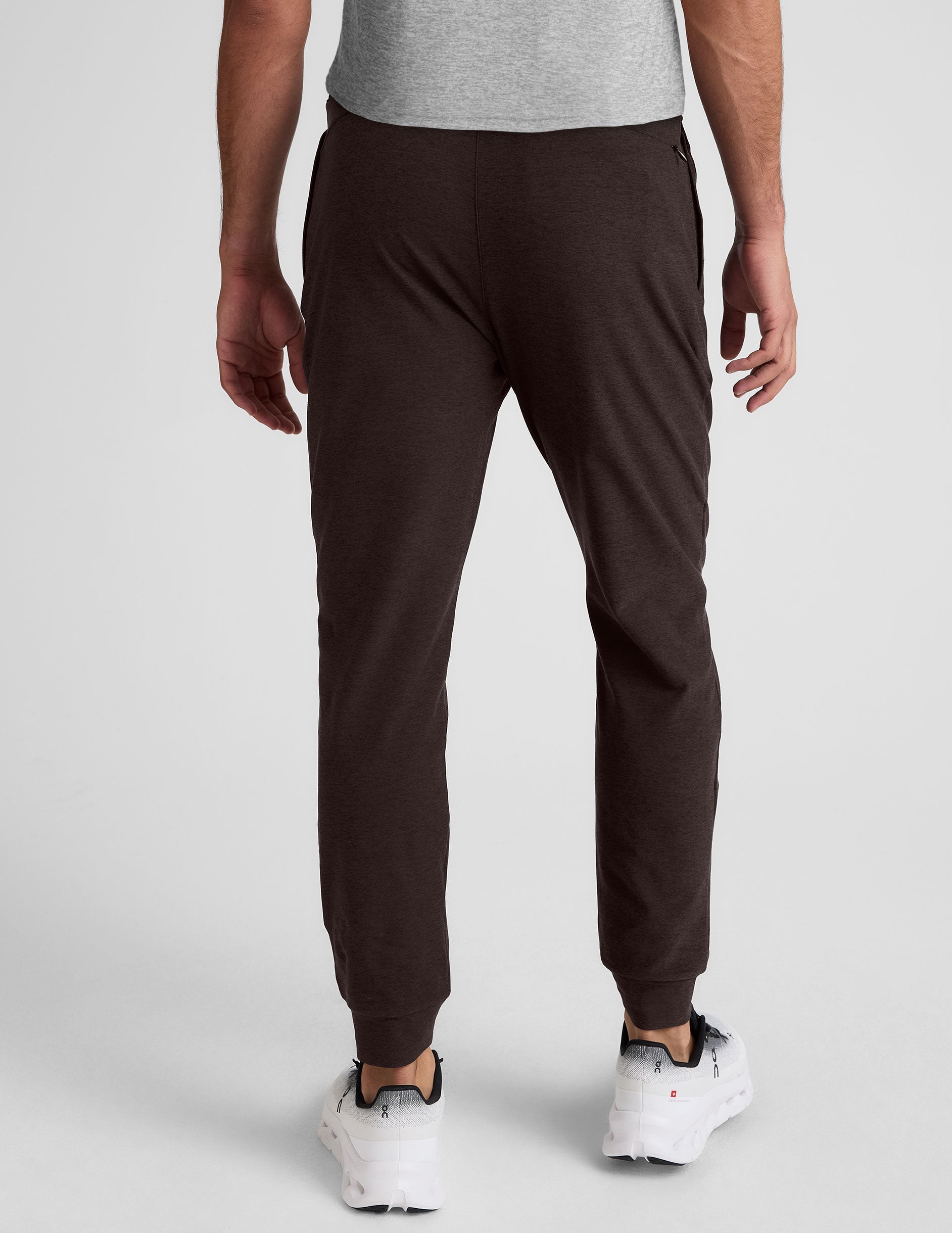 man wearing brown joggers on a plain background.