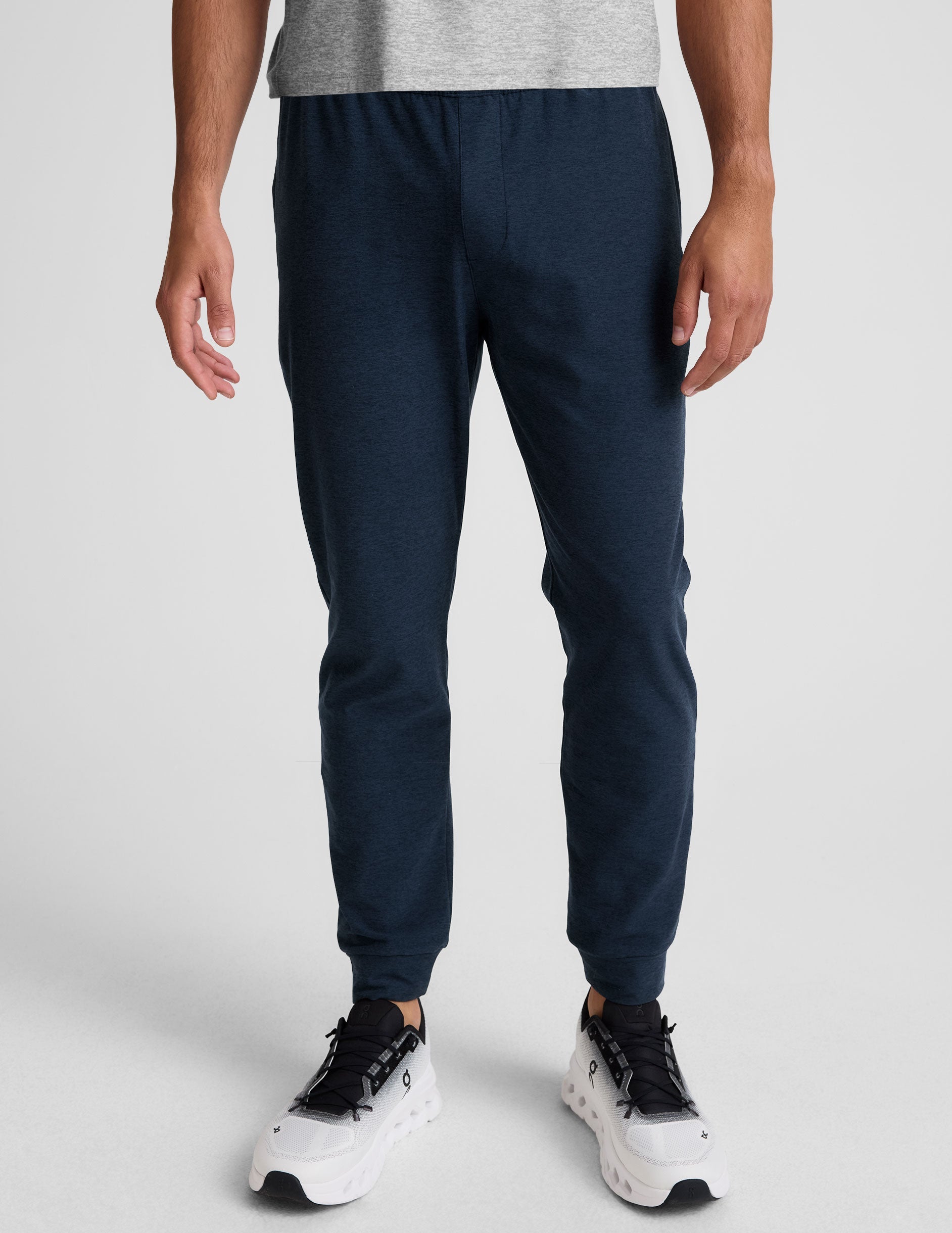 grey t-shirt and navy jogger pants on a plain background.