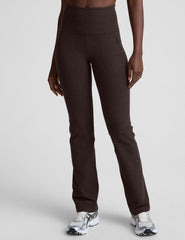woman wearing a brown sports bra and mid-rise pants on a white background.