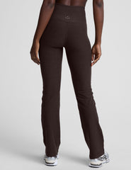woman wearing a brown sports bra and mid-rise pants on a white background.