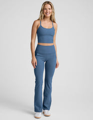 woman wearing a blue cropped tank and blue pants on a plain background.