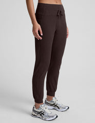 woman wearing a brown joggers with pockets on a light gray background.