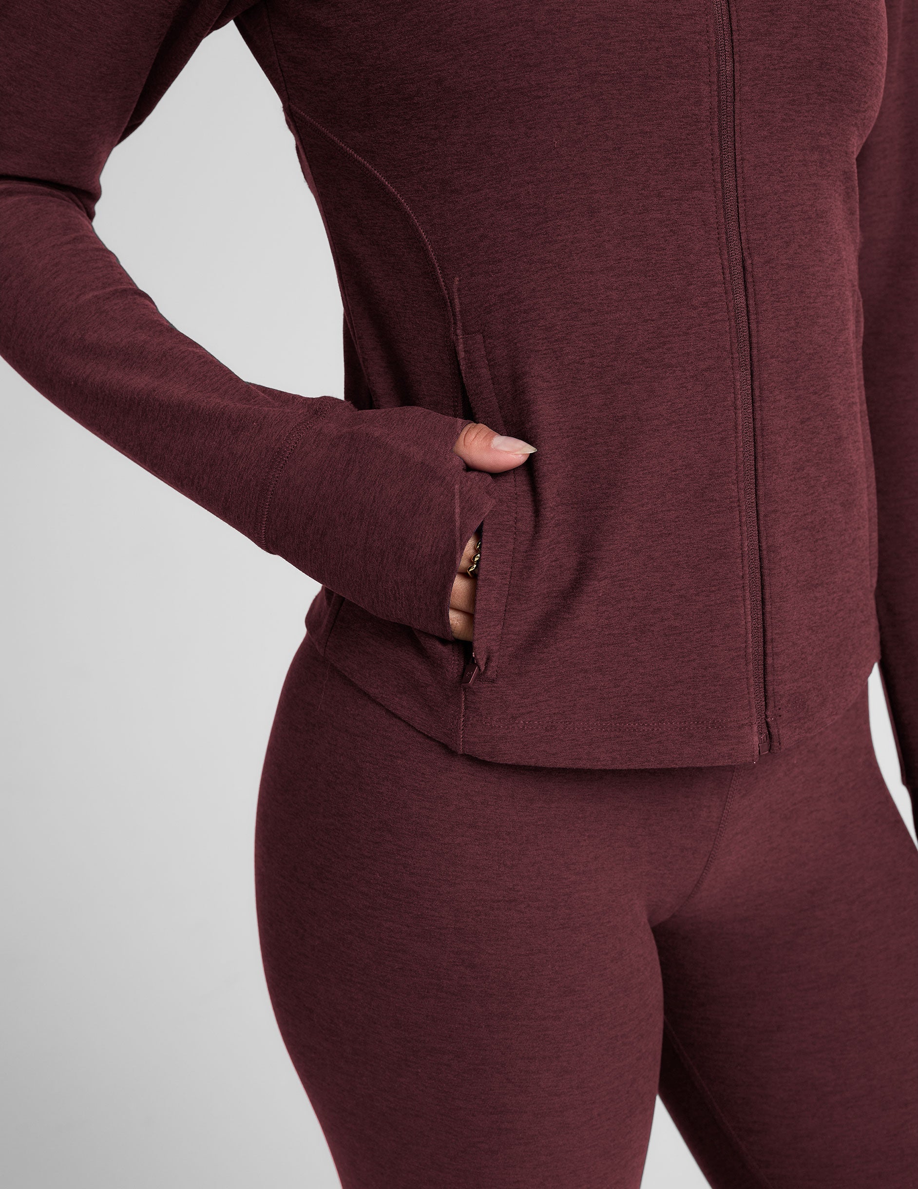 red zip-up mock neck jacket with pockets and thumbholes.