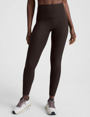 woman wearing a brown sports bra and long leggings set on a white background.