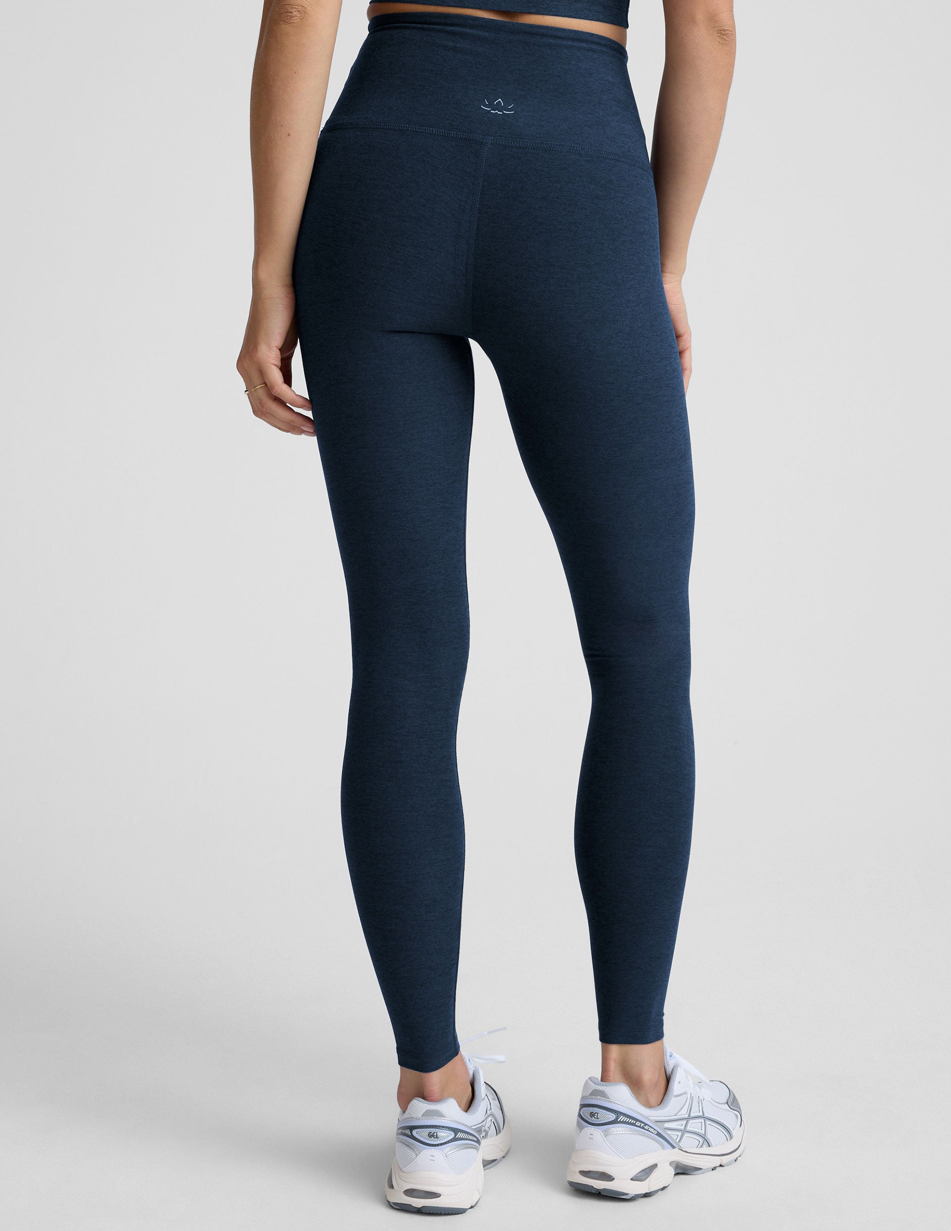 woman is wearing blue high-waisted midi length leggings against a plain background.