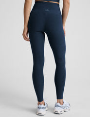 woman is wearing blue high-waisted midi length leggings against a plain background.