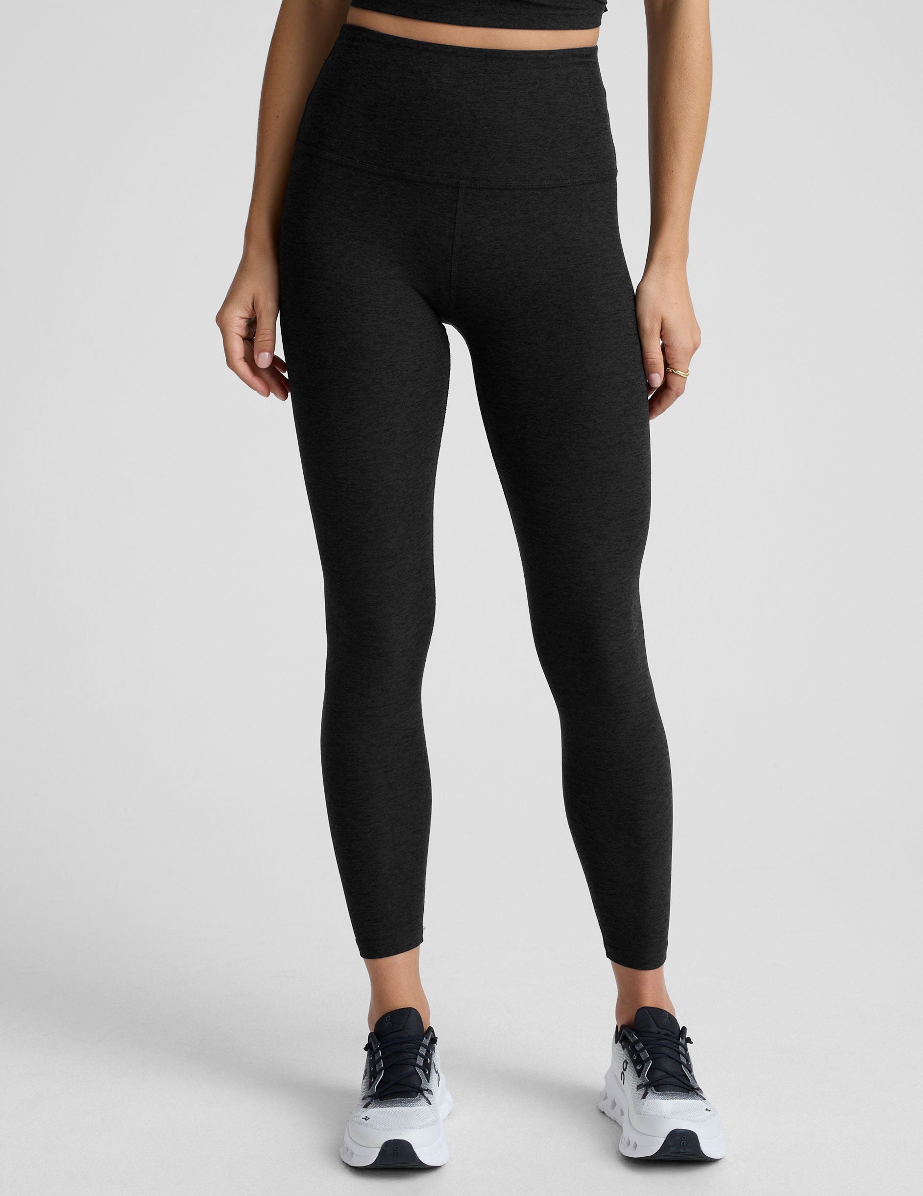 model wearing black high-waisted midi leggings on a white background.