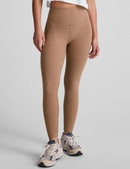 model is wearing brown high-waisted midi leggings and a white tank top.