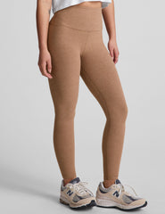 model is wearing brown high-waisted midi leggings and a white tank top.