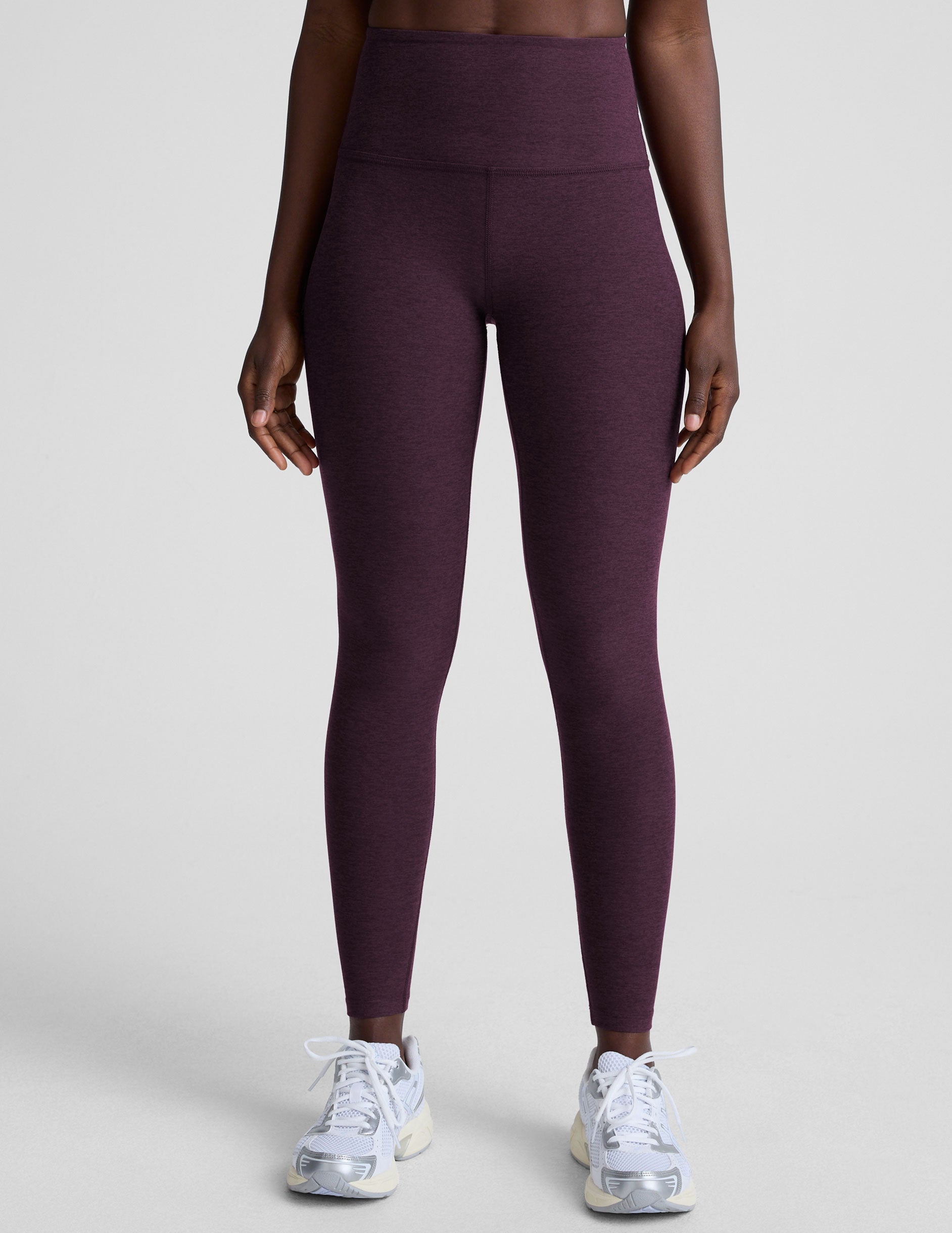 model wearing purple high-waisted midi length leggings  on a light background.