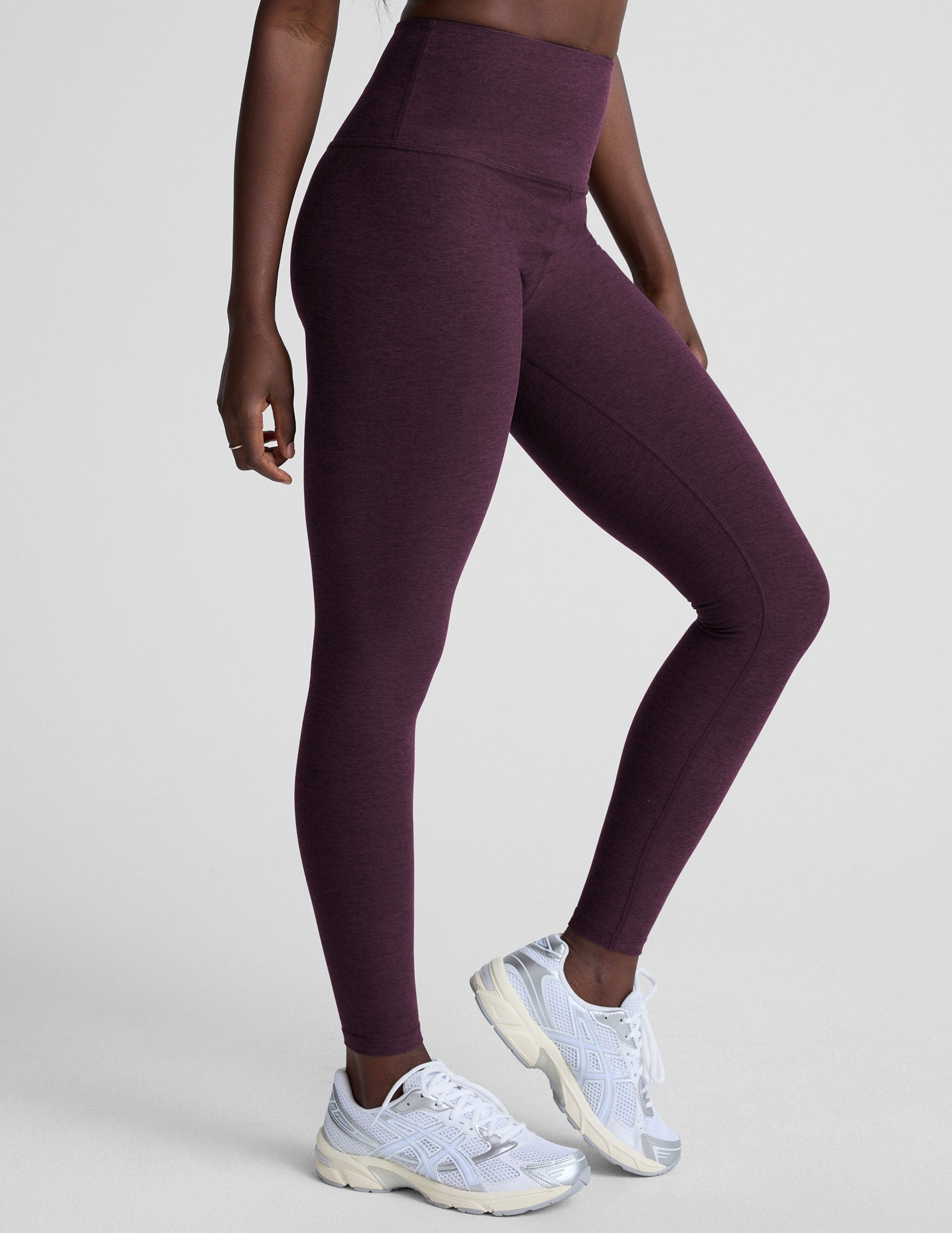 model wearing purple high-waisted midi length leggings  on a light background.