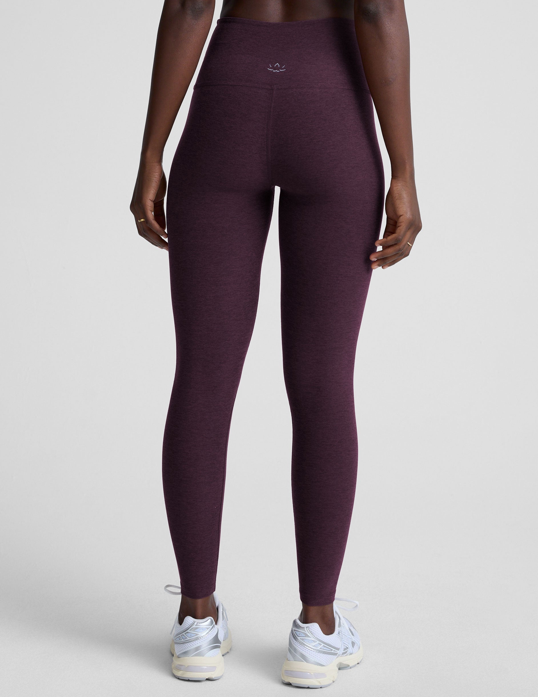 model wearing purple high-waisted midi length leggings  on a light background.