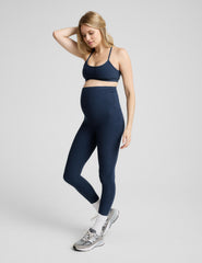 pregnant woman wearing a blue racerback bra and blue maternity midi leggings.