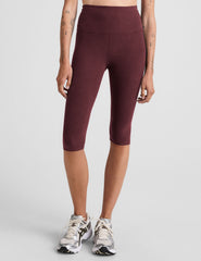 model is wearing red high-waisted pedal pusher length leggings.