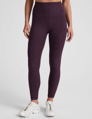 model wearing a purple t-shirt and purple high-waisted midi length leggings with pockets on a light gray background.