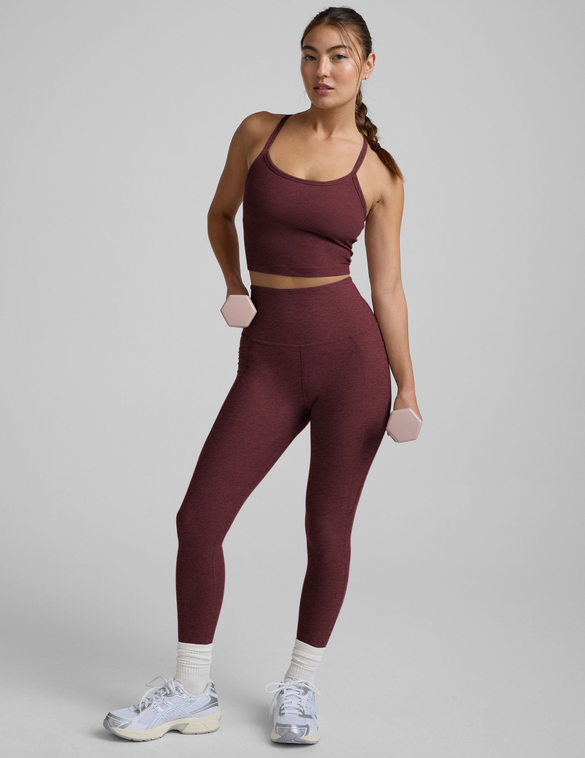Woman wearing a maroon athletic outfit on a gray background