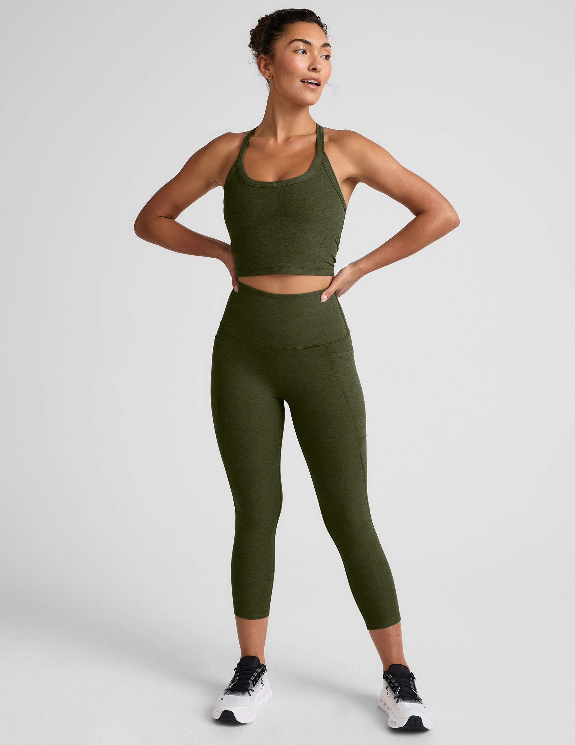 Woman wearing an olive green athletic outfit on a light gray background