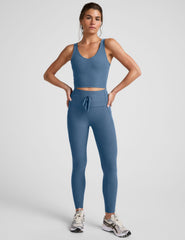Woman wearing a denim blue athletic outfit on a light gray background