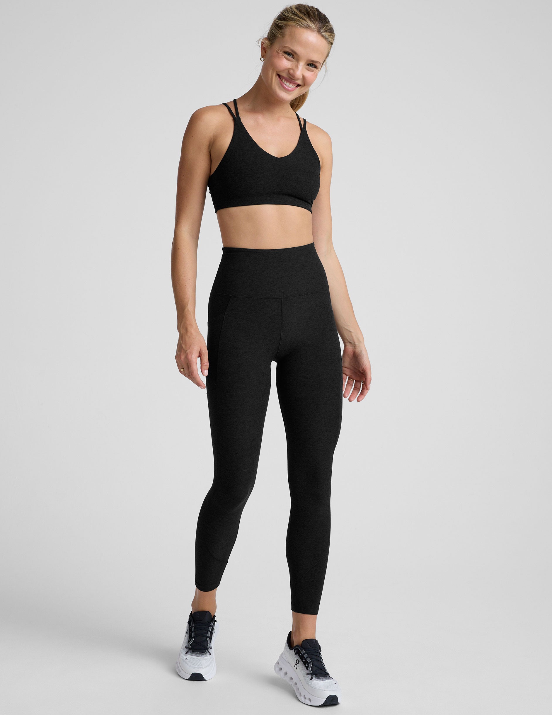 model wearing black midi length leggings with 3 pockets against a plain background.