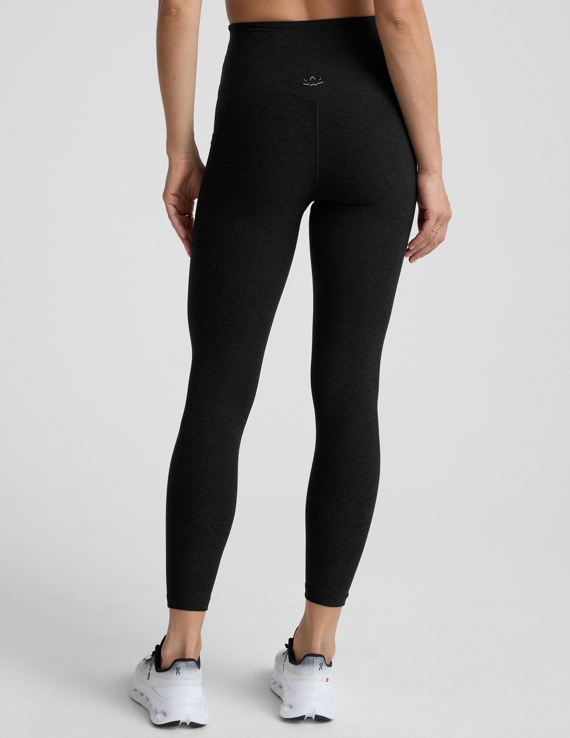 model wearing black midi length leggings with 3 pockets against a plain background.