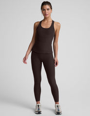 woman wearing a brown racerback and full length tank top and leggings on a plain background.