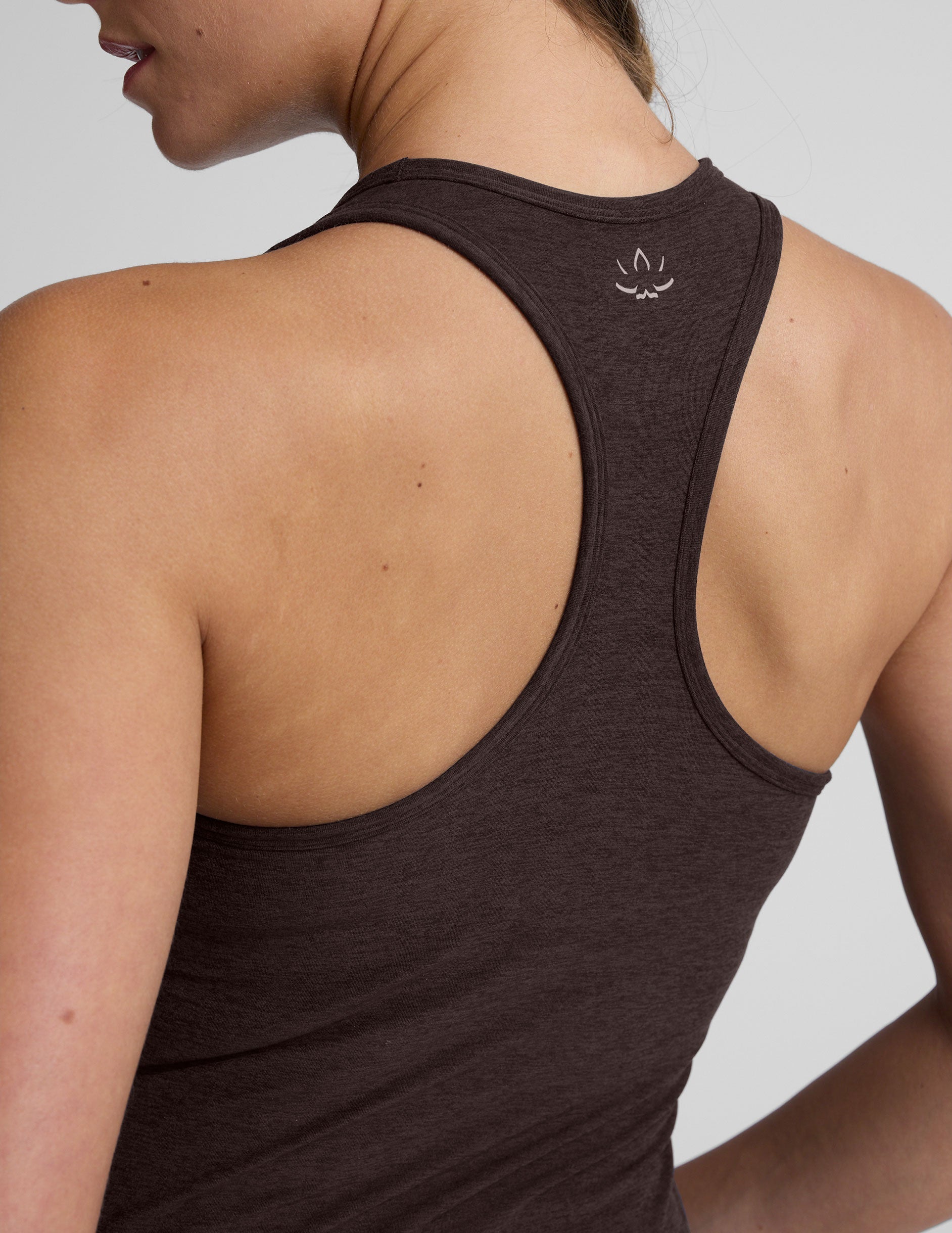 woman wearing a brown racerback and full length tank top and leggings on a plain background.