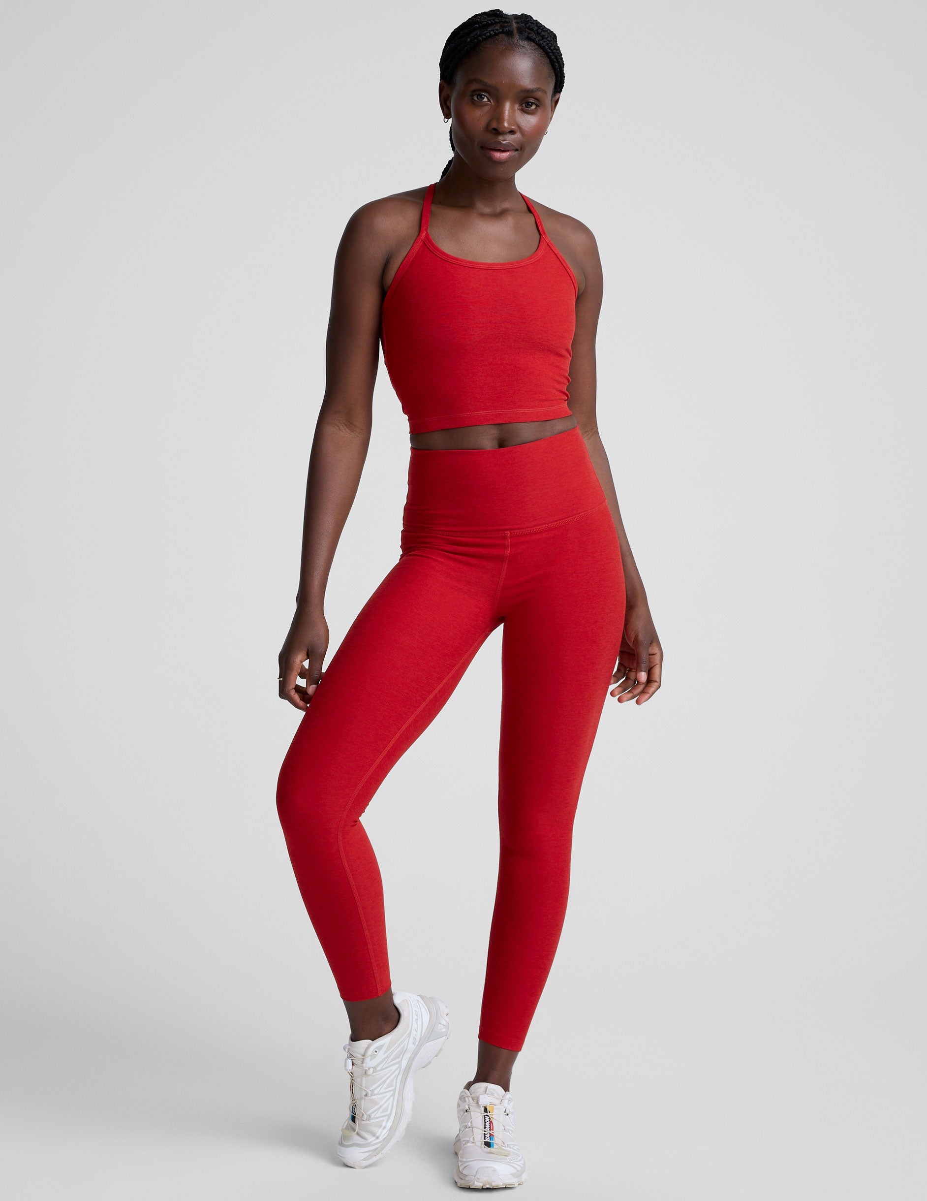 woman wearing a red slim racerback cropped tank and leggings against a plain background.