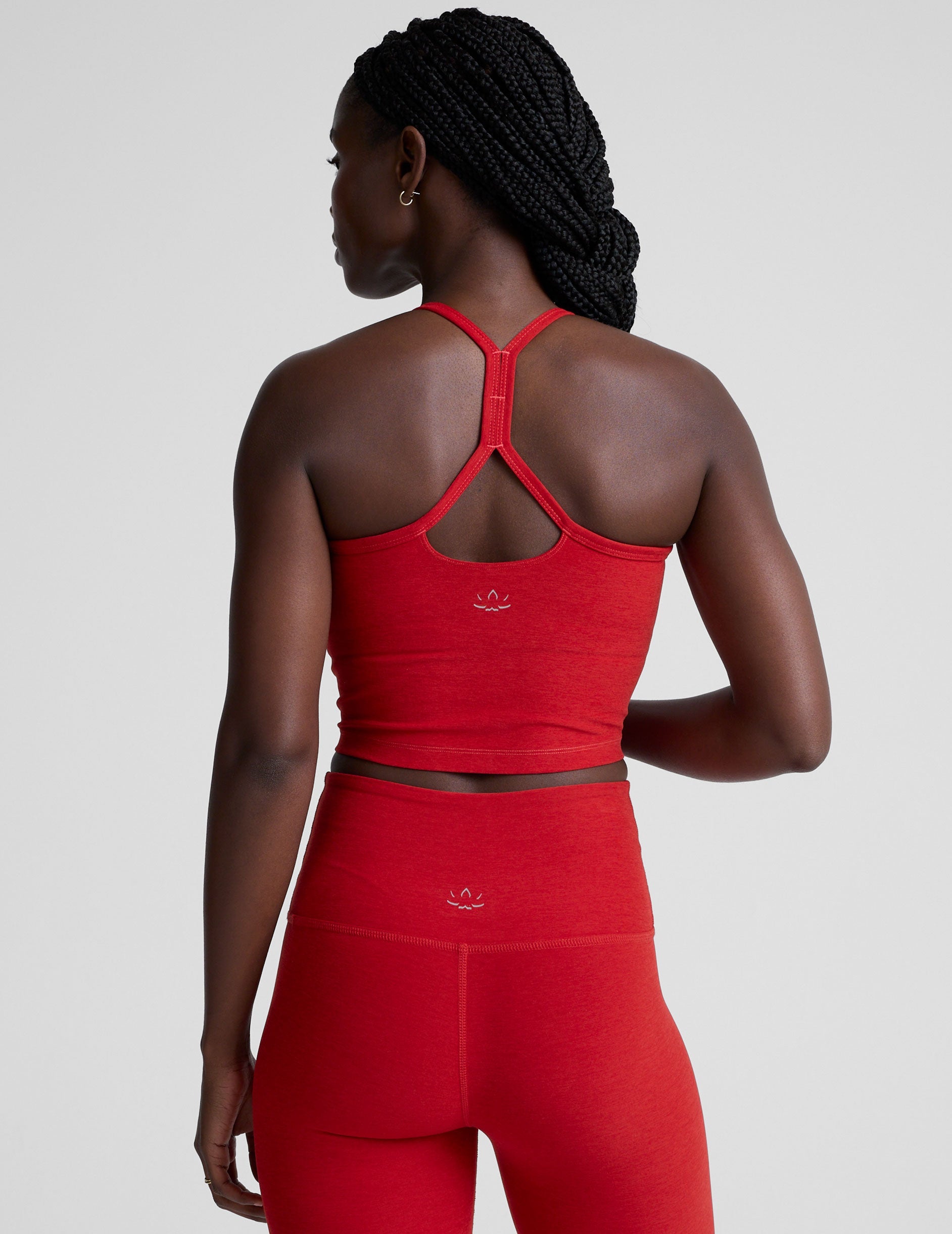 woman wearing a red slim racerback cropped tank and leggings against a plain background.