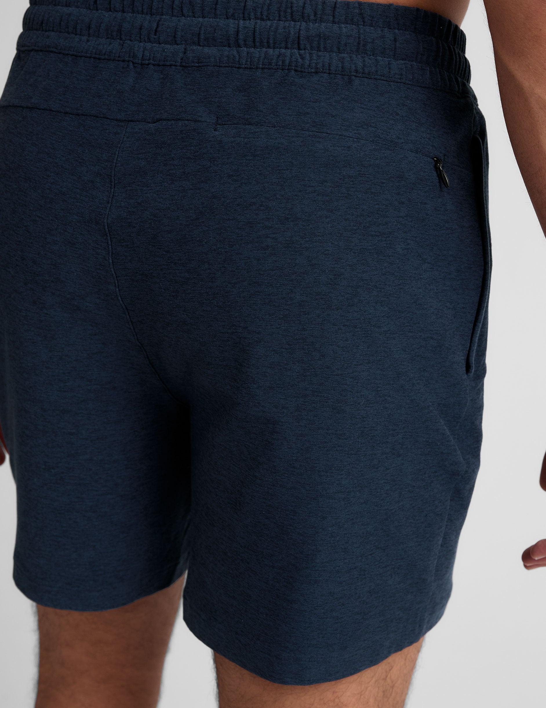 man wearing a grey t-shirt and navy blue shorts on a plain background.