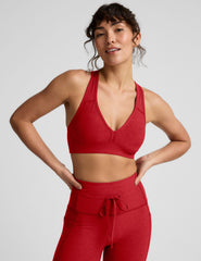 Woman wearing a red v-neck bra and leggings on a light background.