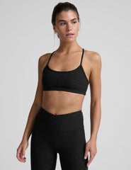 woman wearing a black slim racerback bra and leggings on a plain background.