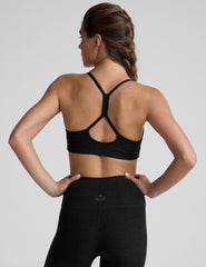 woman wearing a black slim racerback bra and leggings on a plain background.