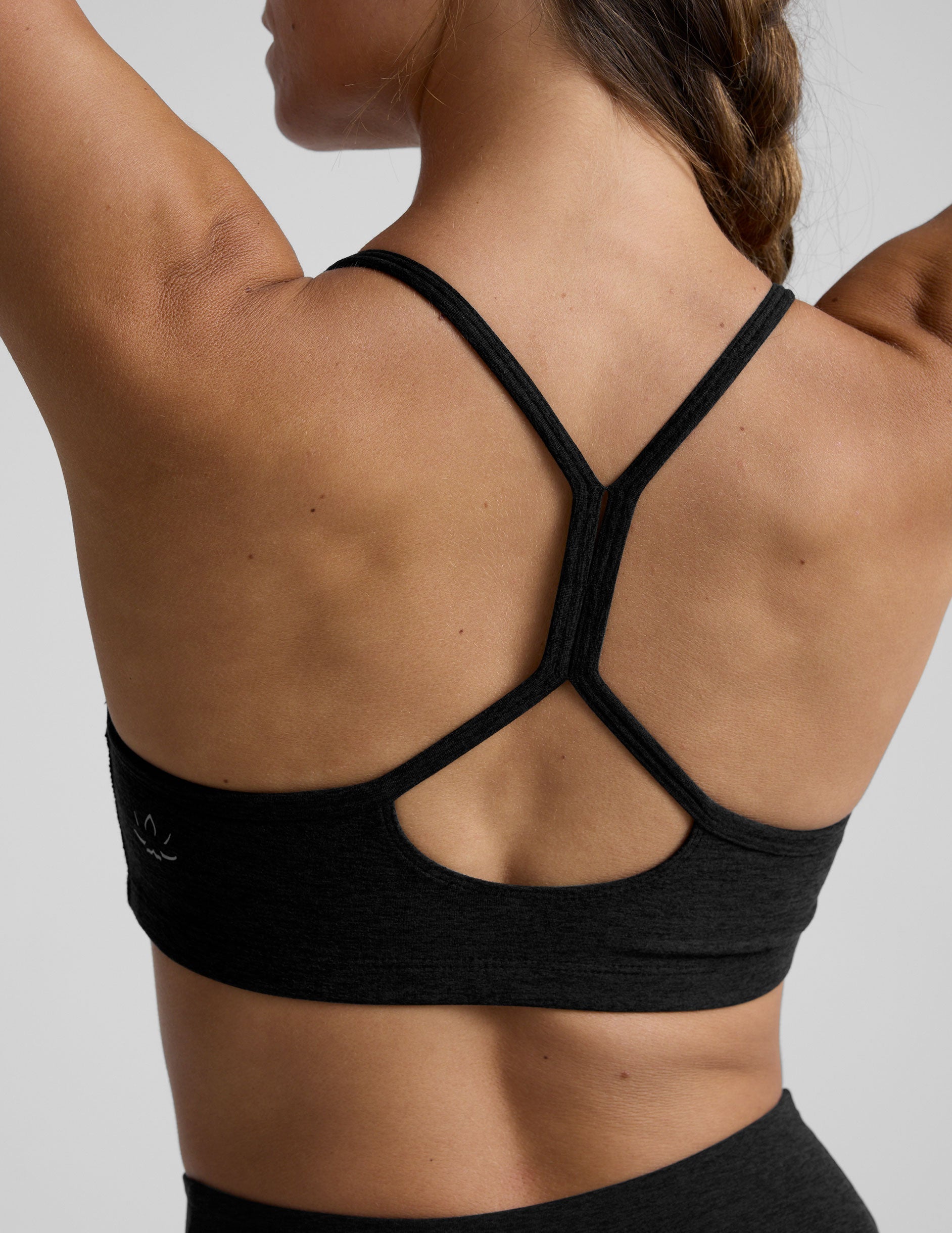 woman wearing a black slim racerback bra and leggings on a plain background.