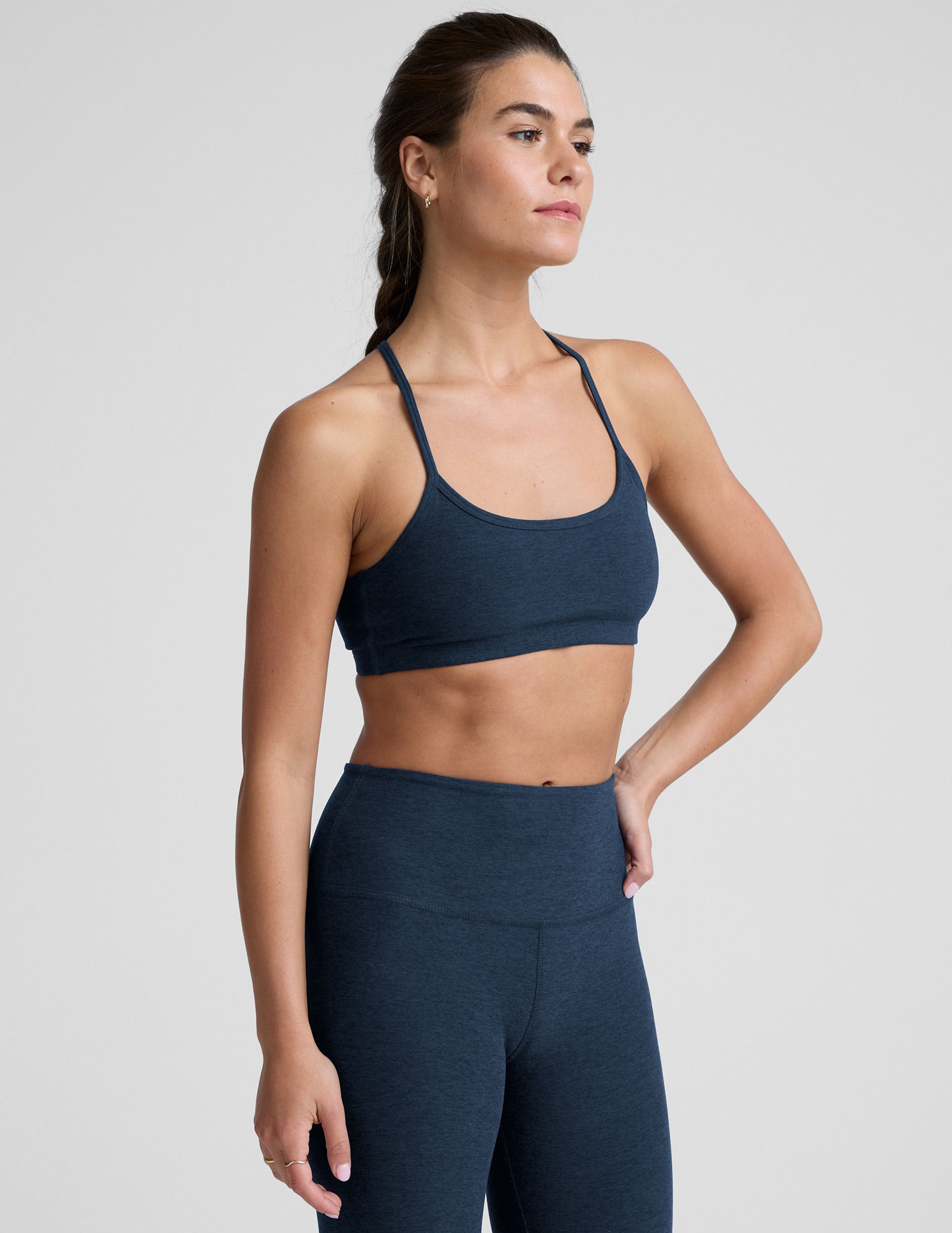 person wearing a blue slim racerback bra with leggings against a plain background.