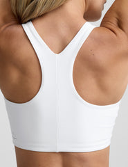 model wearing a white high-neck racerback sports bra and black leggings on a light gray background.